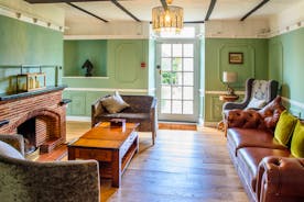 An elegant music lounge with chairs and sofa around a brick fireplace and large coffee table at Forest House holiday home - www.bhhl.co.uk