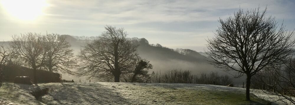 Sun shining through on a frosty and misty winters morning .||View from garden across the valley.