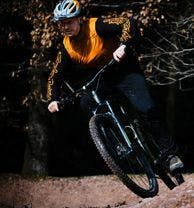 Image shows a man cycling on a mountain bike through the Forest of Dean