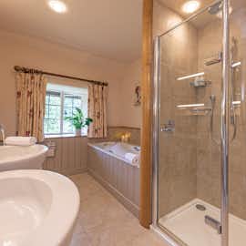 Big Thatch, Devon - Bedroom 1 has an ensuite bathroom with a bath, shower and two handbasins Big Thatch, Devon - Bedroom 1 has an ensuite bathroom with a bath, shower and two handbasins
