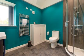Orchard House shower room with turquoise painted walls a white cupboard and a heated towel rail.  - www.bhhl.co.uk