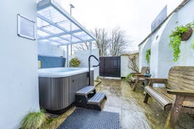 A paved yard with sliding gate, benches and a hot tub with a clear awning cover at Forest House, Coleford  - www.bhhl.co.uk