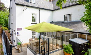 The patio area with large green parasol at the back of Forest House, a holiday rental house in Coleford, Forest of Dean  - www.bhhl.co.uk