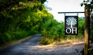  A country road and track leading to Orchard House with the focus on the hanging sign with the house logo  - www.bhhl.co.uk