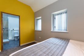 A double bedroom at Orchard House with feature yellow wall and and en suite shower room  - www.bhhl.co.uk