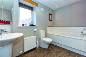 A bathroom at Orchard House with white suite red framed mirror and ornamental shark on the windowsill  - www.bhhl.co.uk