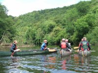 A group of people are canoeing on the river wye surrounded by lush green trees