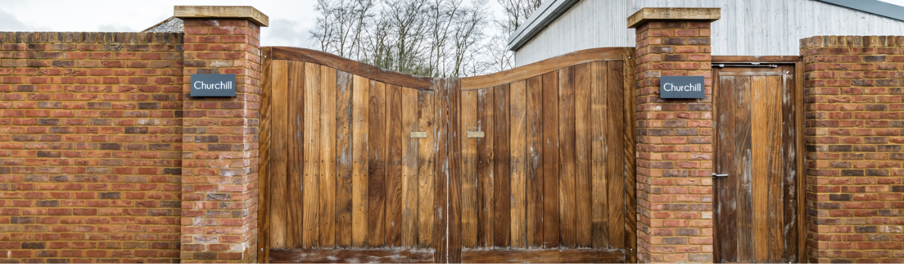 Closed doubles gates with two red brick pillars either side at the entrance to the holiday home churchill.