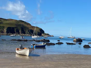 A lovely view of a wide variety of boats sailing in the sea on the Dorset coast near a large cliff
