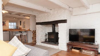 Living room in Driftwood Cottage with a warm, cosy log burning stove and a TV