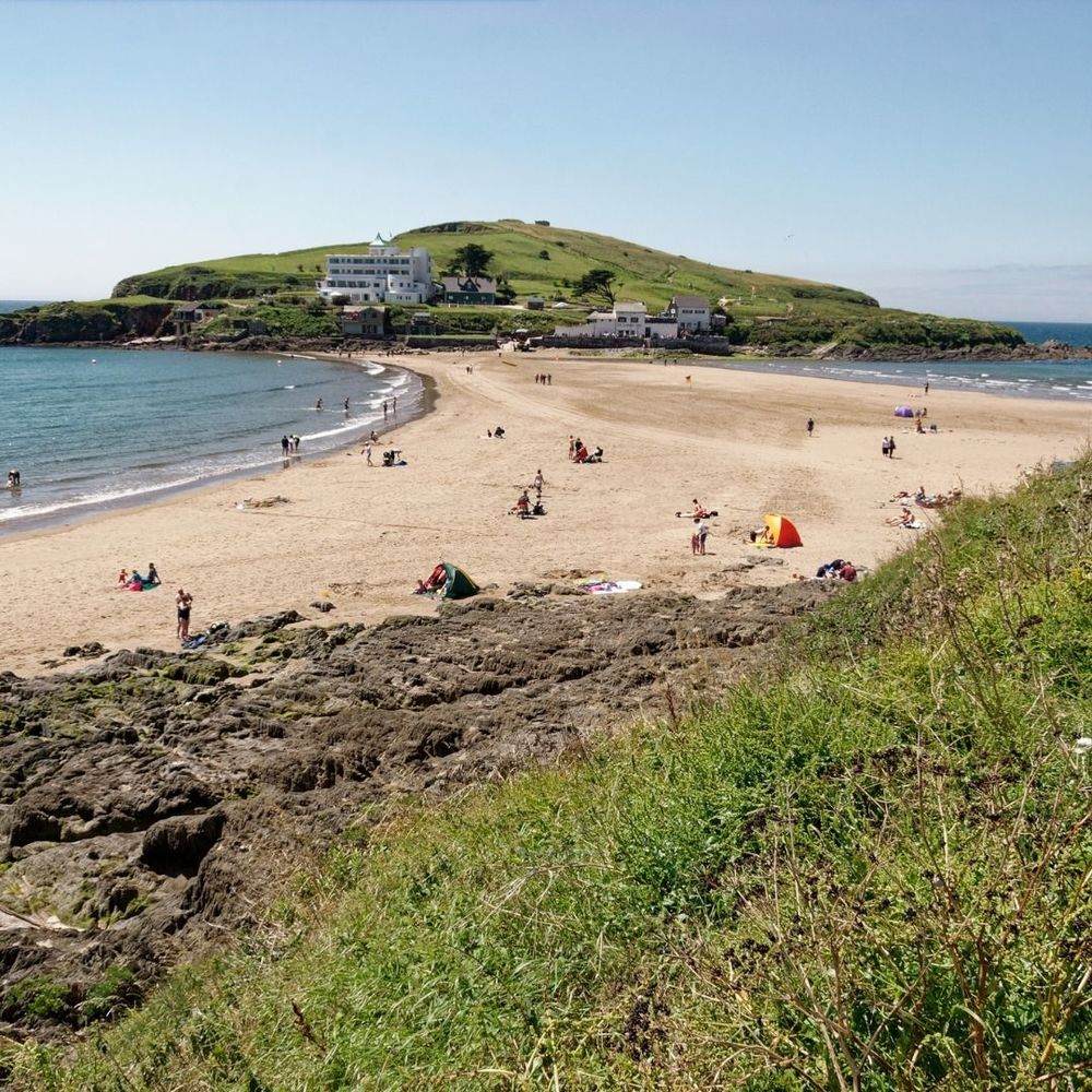 An outstanding sandy beach on Bigbury-On-Sea surrounded by the clear, stunning sea and grassy hills