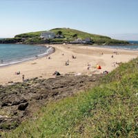 An outstanding sandy beach on Bigbury-On-Sea surrounded by the clear, stunning sea and grassy hills