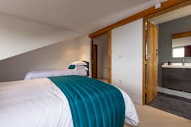 A twin bedroom with wooden doors leading to en suite bathroom at Orchard House accommodating friends  - www.bhhl.co.uk