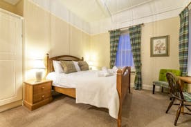 Double bedroom with twin windows with long curtains, matching chair covers, at Forest House, in the centre of Coleford - www.bhhl.co.uk