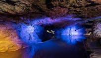 Beautiful image of Clearwell Caves showing blue light reflecting on one of the indoor lakes