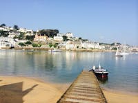 Stunning view of East Portlemouth Beach's long sandy shore, clear sea and multiple houses, ferries and other types of boats