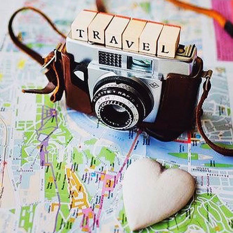 vintage camera on a map with scrabble letters saying travel