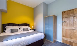 Orchard House double bedroom with yellow feature wall and wooden door  - www.bhhl.co.uk