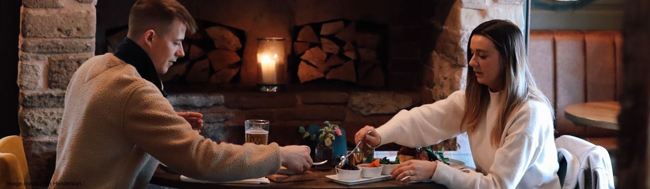 A couple having a meal in a restaurant beside a fire